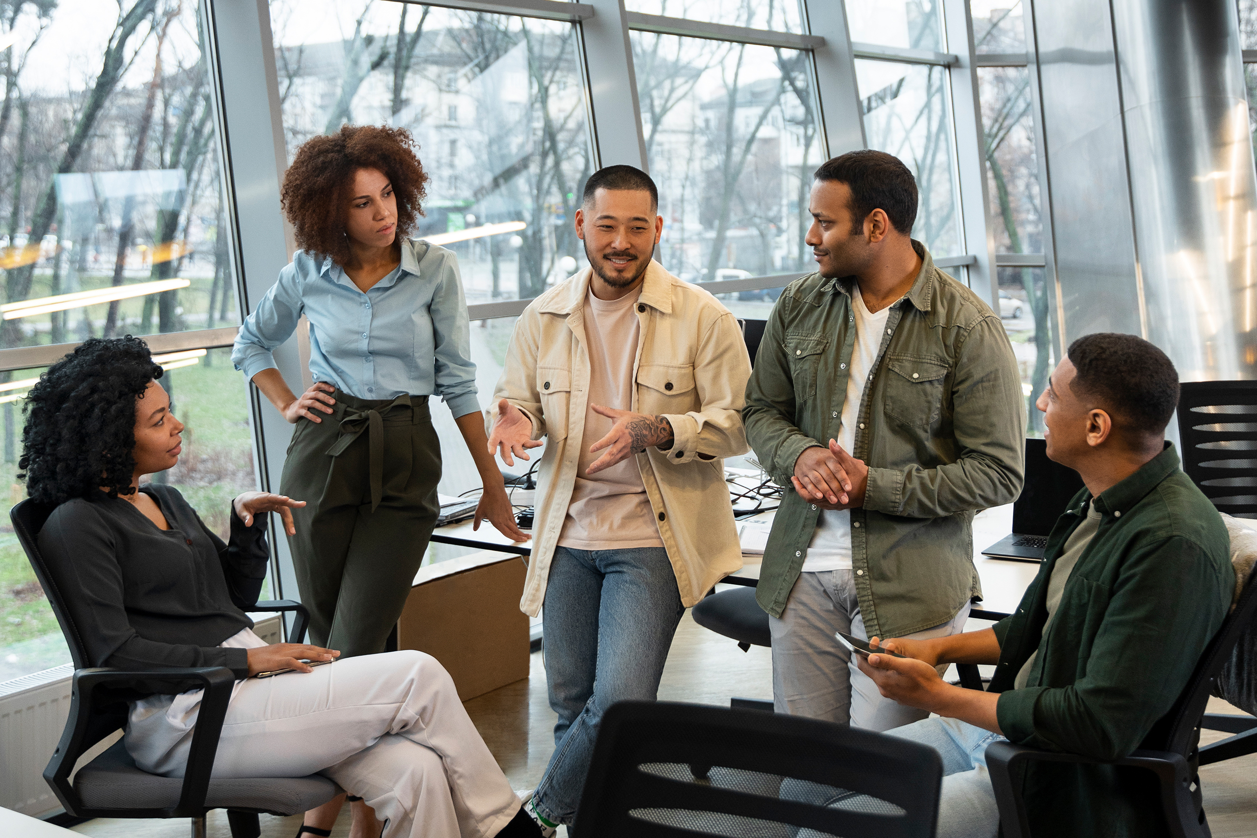 A group of diverse coworkers collaborating in a modern office, gathered around a table and engaged in a discussion.