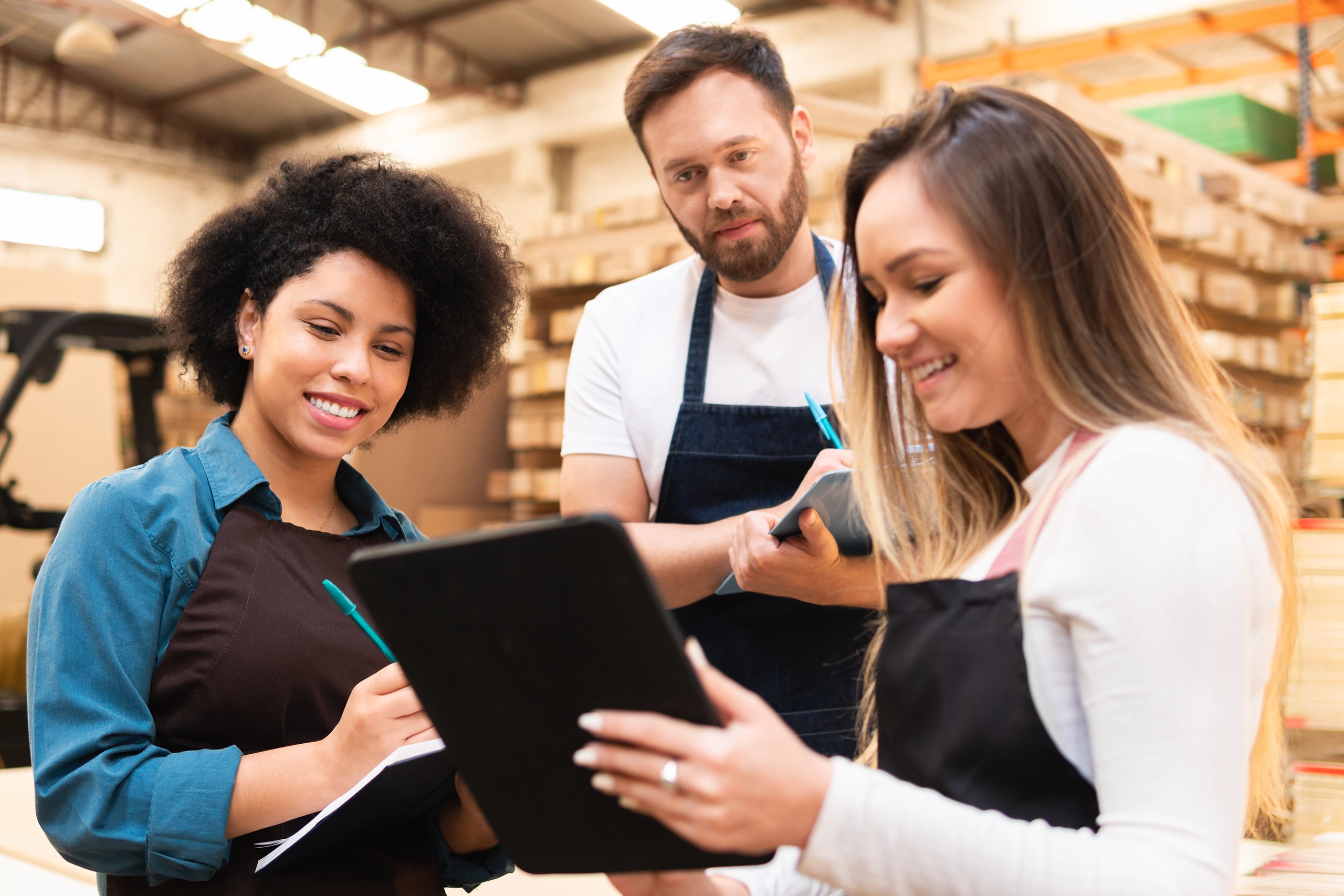 Three employees review information on a tablet during seasonal employee onboarding and compliance training.